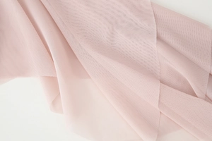 Detailed macro view of pink mesh fabric showing fine texture and ruffled pleats on the blouse