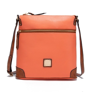 Close-up of coral orange pebbled leather crossbody bag with brown trim and gold zipper