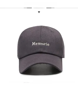 Detailed view of white Memorie letter embroidery on a dark grey cotton baseball cap