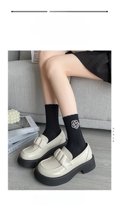 Detail of black ribbed mid-calf socks featuring a white camellia floral accessory