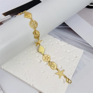 18K gold plated copper ocean bracelet with shell and starfish charms on a white stone