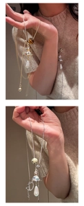 Detail of Saturn orb necklace with tiger eye beads and faux pearl pendant on a model