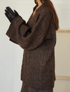 Detailed close-up of brown cable-knit texture and soft sleeve of the thick winter sweater