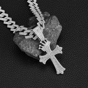 Gros plan d'un collier chaîne cubaine argentée avec pendentif croix couronne givrée
