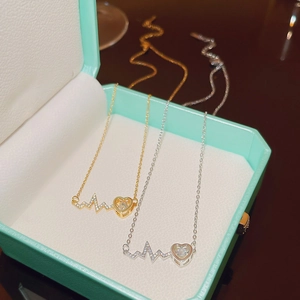 Detailed close-up of heart and heartbeat pendants in gold and silver on a jewelry box