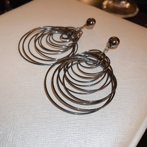 Detail of oversized multi-layered gunmetal hoop earrings with polished finish