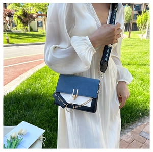 Detail of color-block crossbody bag with gold buckle and patterned wide shoulder strap