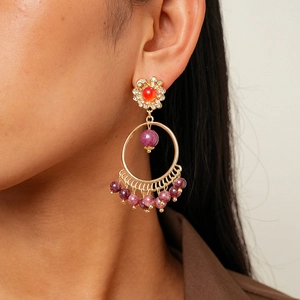 Detail of vintage tassel earrings with gold flowers, red beads and purple stones