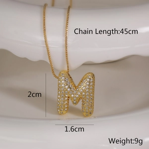 Detailed view of gold M letter pendant with clear zircon inlay and size dimensions