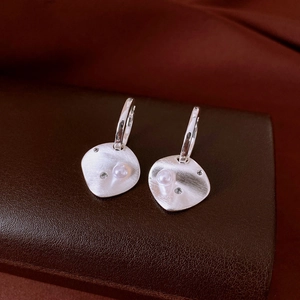 Detail view of silver rhombic earrings with brushed texture, pearl, and zircon inlay