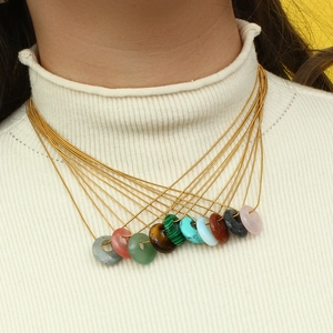 Layered gold necklaces with various colorful natural stone round pendants on a model