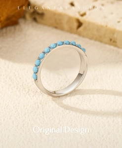 Primo piano di un anello in argento S925 con pietre turchesi incastonate sulla sabbia