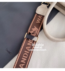 Detail of jacquard webbing shoulder strap with golden D-ring buckle on cream tote bag