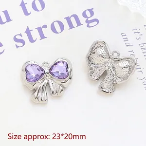 Macro detail of silver bow pendants with purple heart gems and size measurement