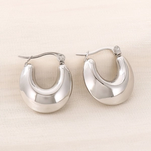 Macro shot of silver polished U-shaped stainless steel hoop earrings on silk