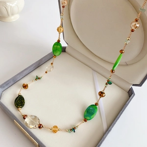 Close-up of bohemian beaded necklace with green and amber stones in a jewelry box
