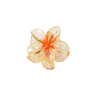 Détail d'une pince à cheveux fleur orange translucide de 4cm avec finition pailletée