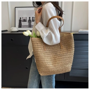 Detail of a large straw tote bag with brown leather straps for summer beach vacations