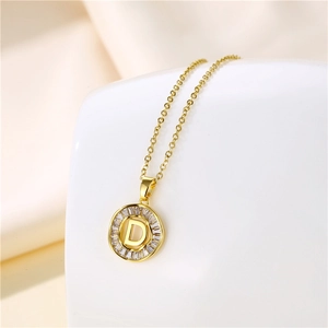 Detailed macro of 18K gold letter D pendant with baguette zircon inlay on silk background