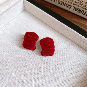 Macro shot of dark red velvet bow earrings with pleated texture on a jewelry tray