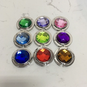 Nine colorful gemstone handbag hooks arranged in a grid on a white marble background