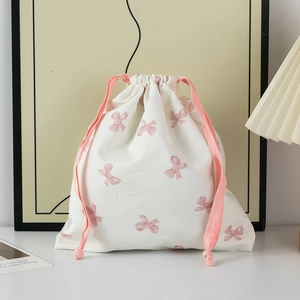 Detail of drawstring storage bag with pink bow pattern on cream fabric in a cozy setting