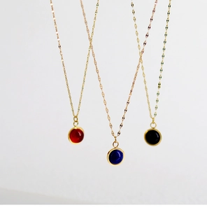 Detailed view of three minimalist 18K gold plated necklaces with red blue and black stones