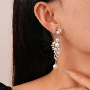 Close-up of elegant long tassel earrings featuring sparkling rhinestones and white pearls