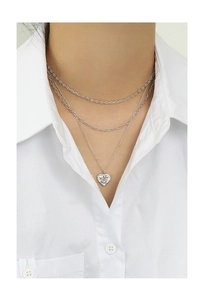 Close-up of triple-layered S925 sterling silver heart necklace worn over a white shirt