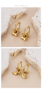 Detail of gold-plated star and moon pendant earrings on a natural white stone base