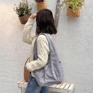 Detailed view of large grey checkered tote bag with pockets on a textured wall background