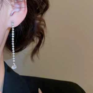 Close-up of long tassel earring with sparkling crystals and a large round gemstone drop