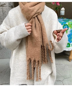 Close-up of soft brown cashmere-like scarf with long tassels on a model in white