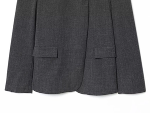 Detail of dark gray blazer featuring woven texture and symmetrical flap pockets on white background