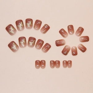 Macro detail of glossy ombre brown press-on nails with golden butterfly and floral patterns