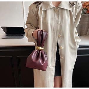 Detail of burgundy leather bucket bag with elegant oversized gold ring hardware