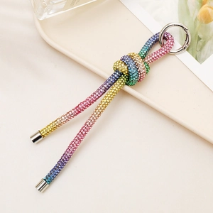 Rainbow gradient rhinestone knot keychain with silver ring on a professional beige tray