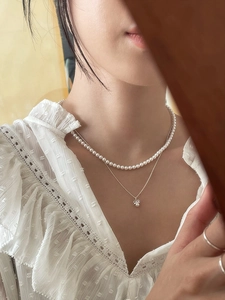 Close-up of double-layer 925 silver necklace with bow and pearl pendant on a model