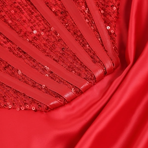 Détail de paillettes rouges et satin sur une robe de soirée sexy à épaules dénudées