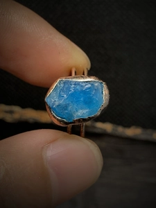 Macro detail of natural irregular blue crystal stone set in vintage copper open ring