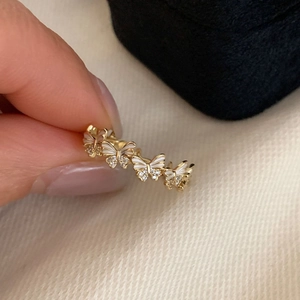 Detail of gold butterfly ring with white enamel wings and sparkling zircon accents