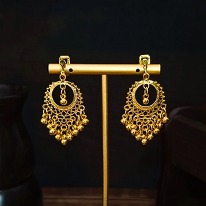 Detailed shot of golden bohemian tassel earrings displayed on a professional T-stand