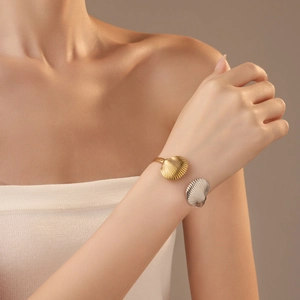 Close-up of golden and silver shell-shaped open cuff bracelet on female wrist