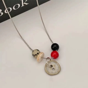 Detail view of retro beaded necklace with silver snake chain and button pendant