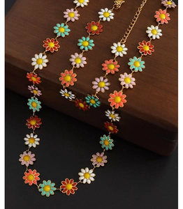 Detail of colorful enamel daisy charms on a metal chain draped over a brown wooden box