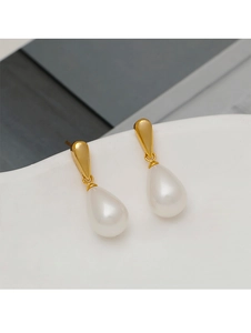 Macro shot of elegant white teardrop pearls suspended from gold-tone metal studs