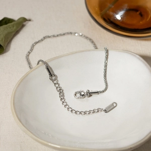 Detail of silver stainless steel double layered anklet with S.STEEL engraved tag