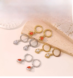 Detail of gold and silver hoop earrings with irregular lava texture and zircon stones
