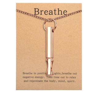 Close-up of rose gold whistle pendant on card with 'Breathe' mindfulness text
