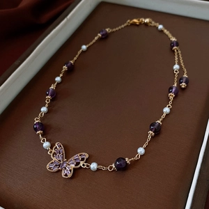 Detail of butterfly necklace with purple crystals, pearls and golden chain in a jewelry box